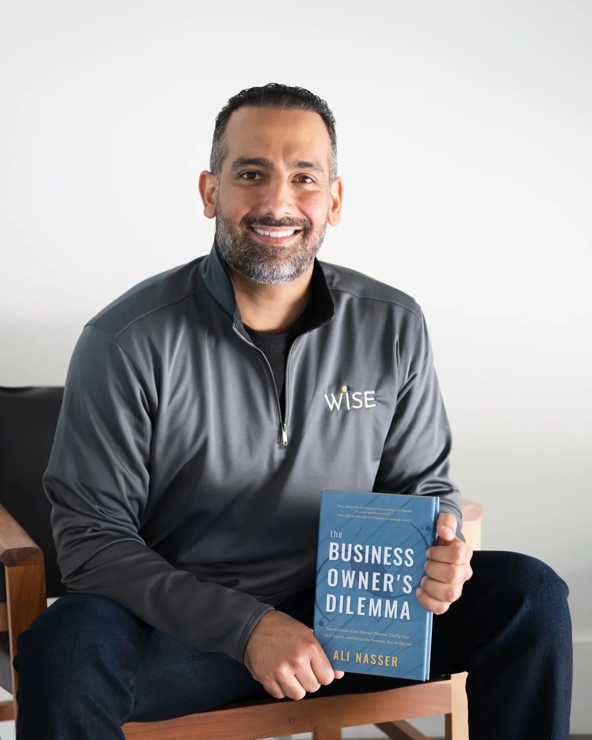 Ali Nasser holding a copy of The Business Owner's Dilemma